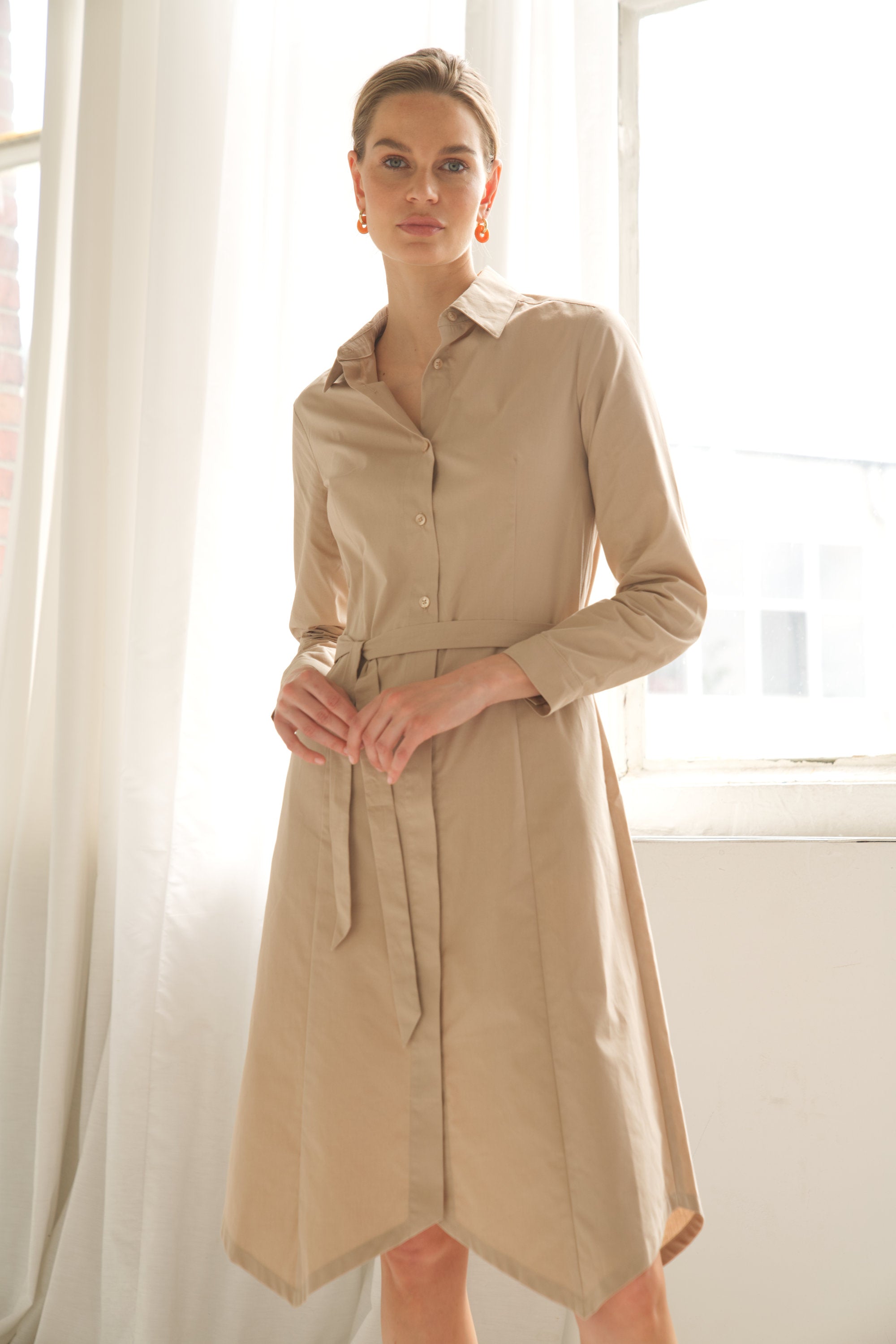 Unser Model trägt ein Hemdblusenkleid in beige von Bellasor. Das Model hat blondes Haar und Sie zeigt das elegante Outfit von vorne.