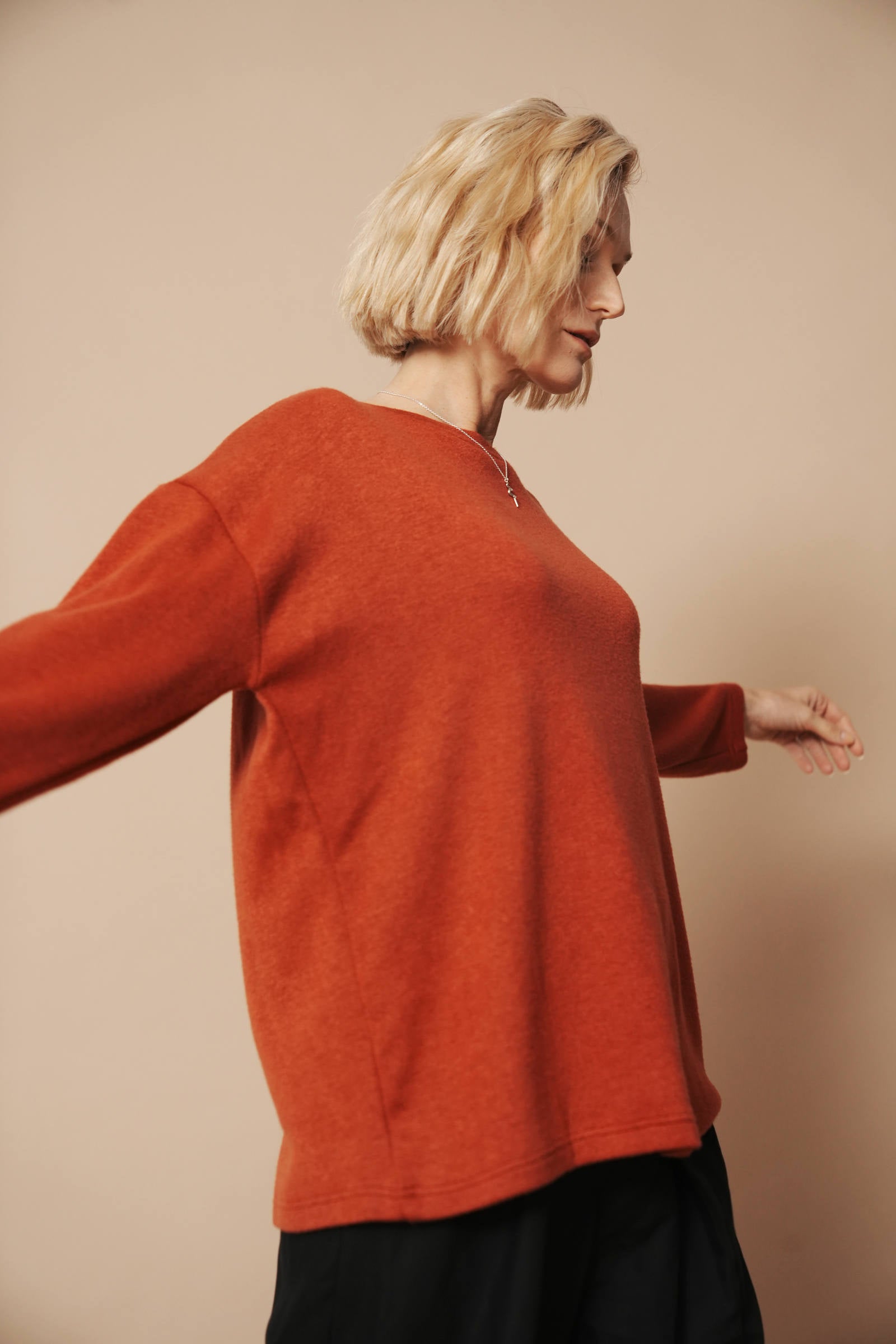 Blondes Model trägt einen hochwertigen Strickpullover für Damen. Sie zeigt die Ansicht von der rechten Seite.