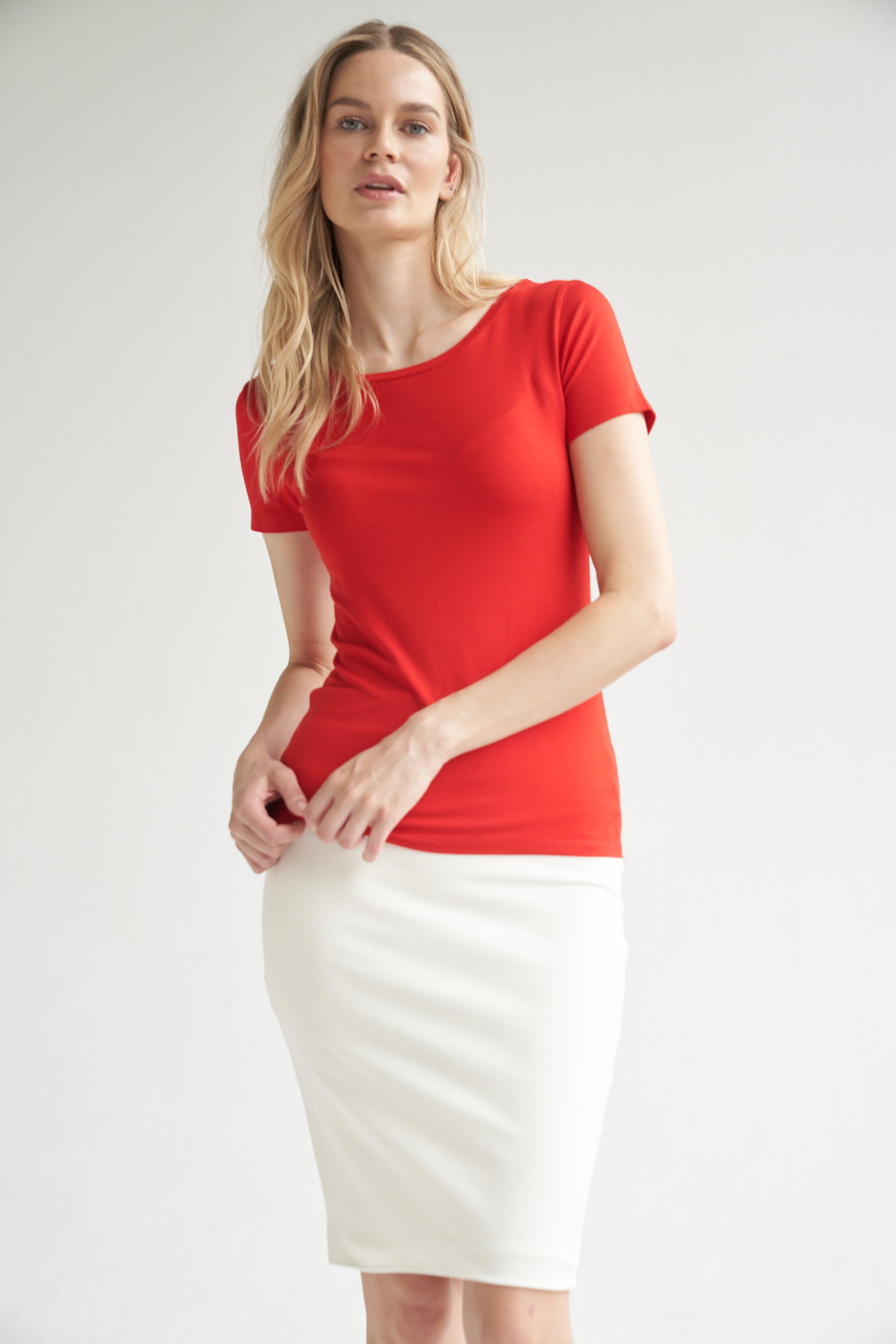 Unser Model trägt einen Bleistiftrock in weiß und ein Shirt in rot von Bellasor. Der Bleistiftrock ist knielang. Das Model hat blondes Haar und zeigt die Ansicht von vorne.