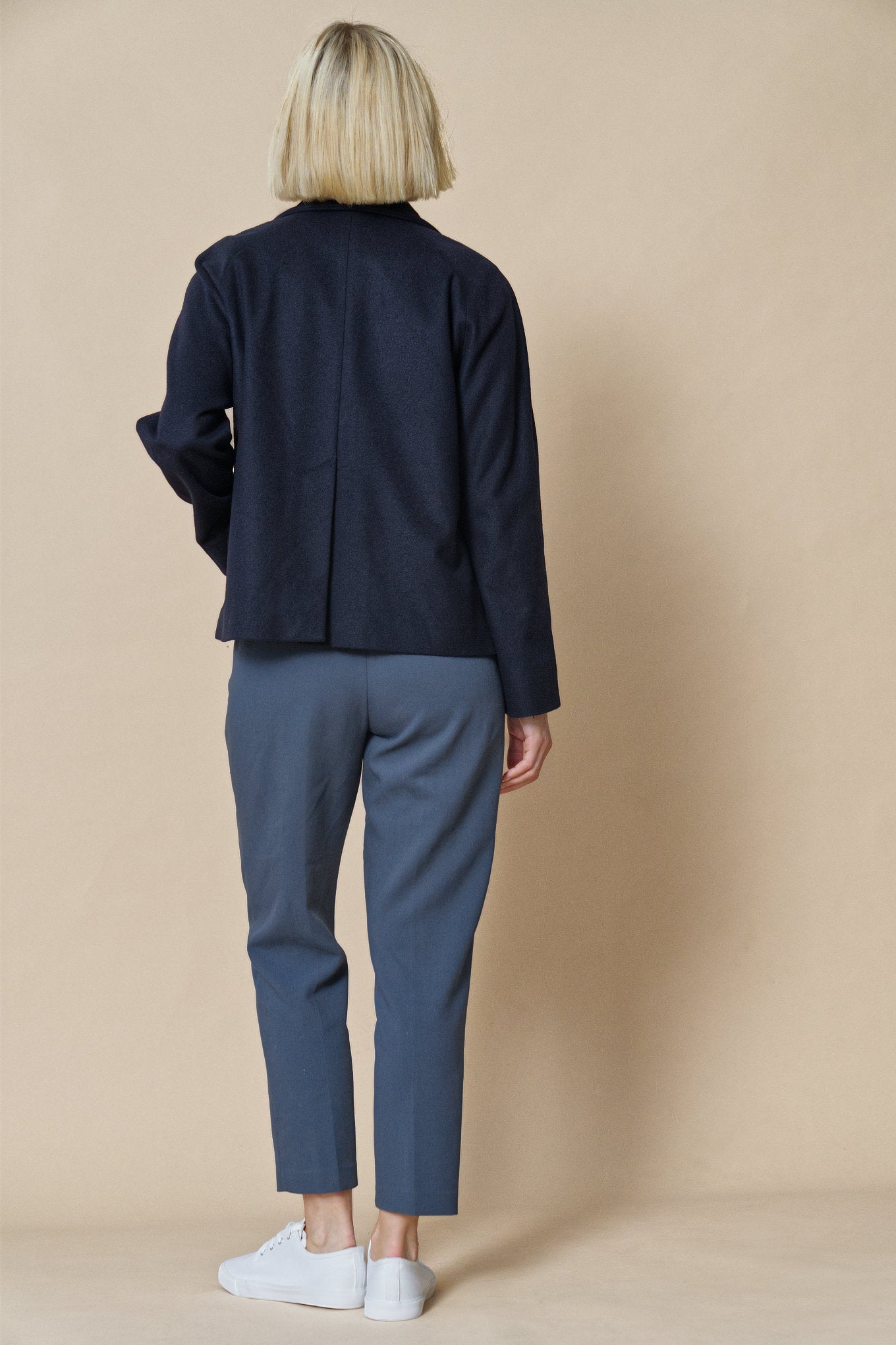 Das Model zeigt unsere Jacke aus Wolle und Kaschmir in der Farbe night blue mit der Ansicht von hinten.