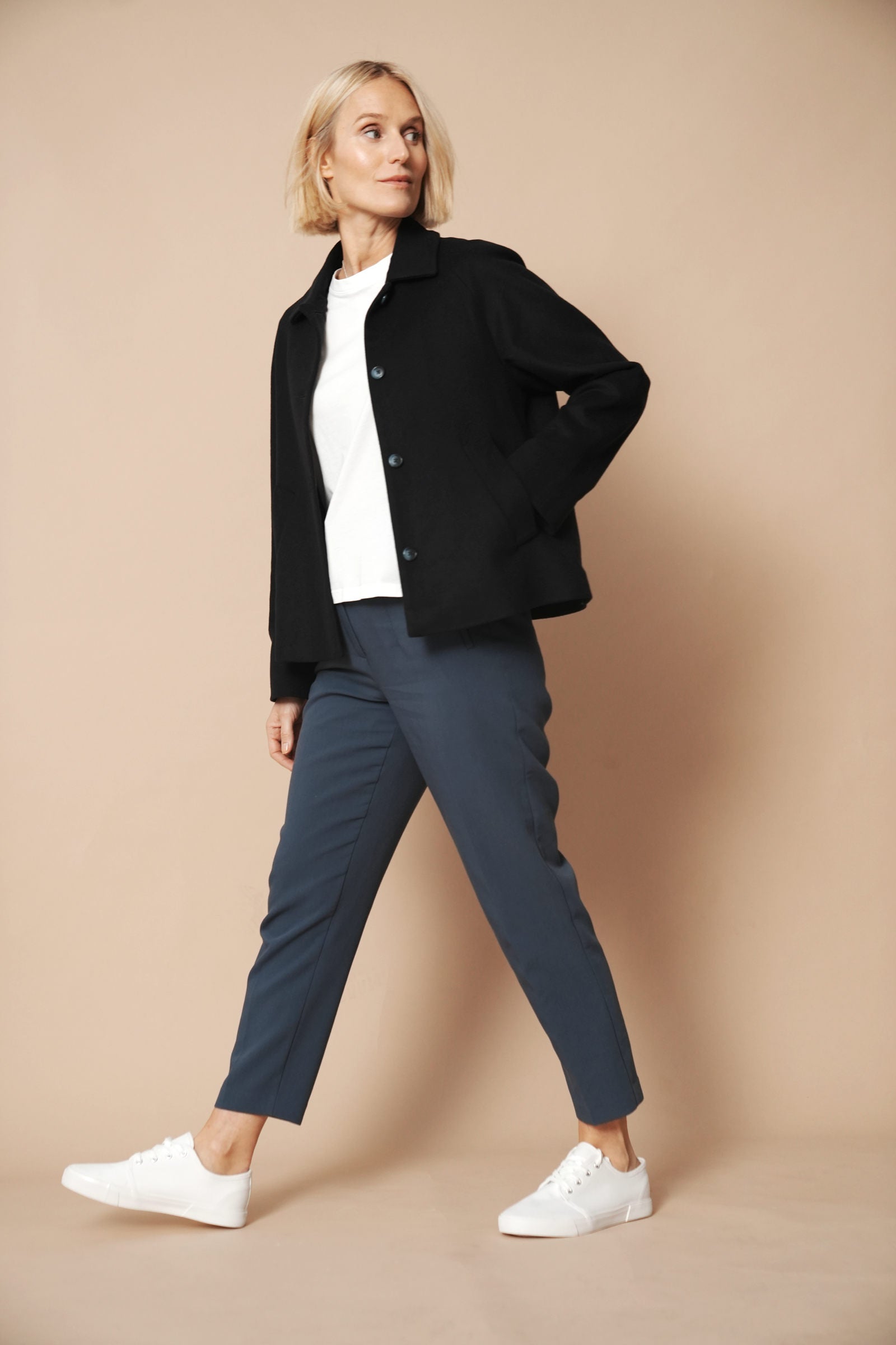 Model trägt eine Jacke aus Wolle und Kaschmir in der Farbe night blue. Gerader Schnit im Boxy-Fit Style. Das Model hat ein Hand in der linken Seitentasche und zeigt die Jacke von der Seite im lässigen gang.