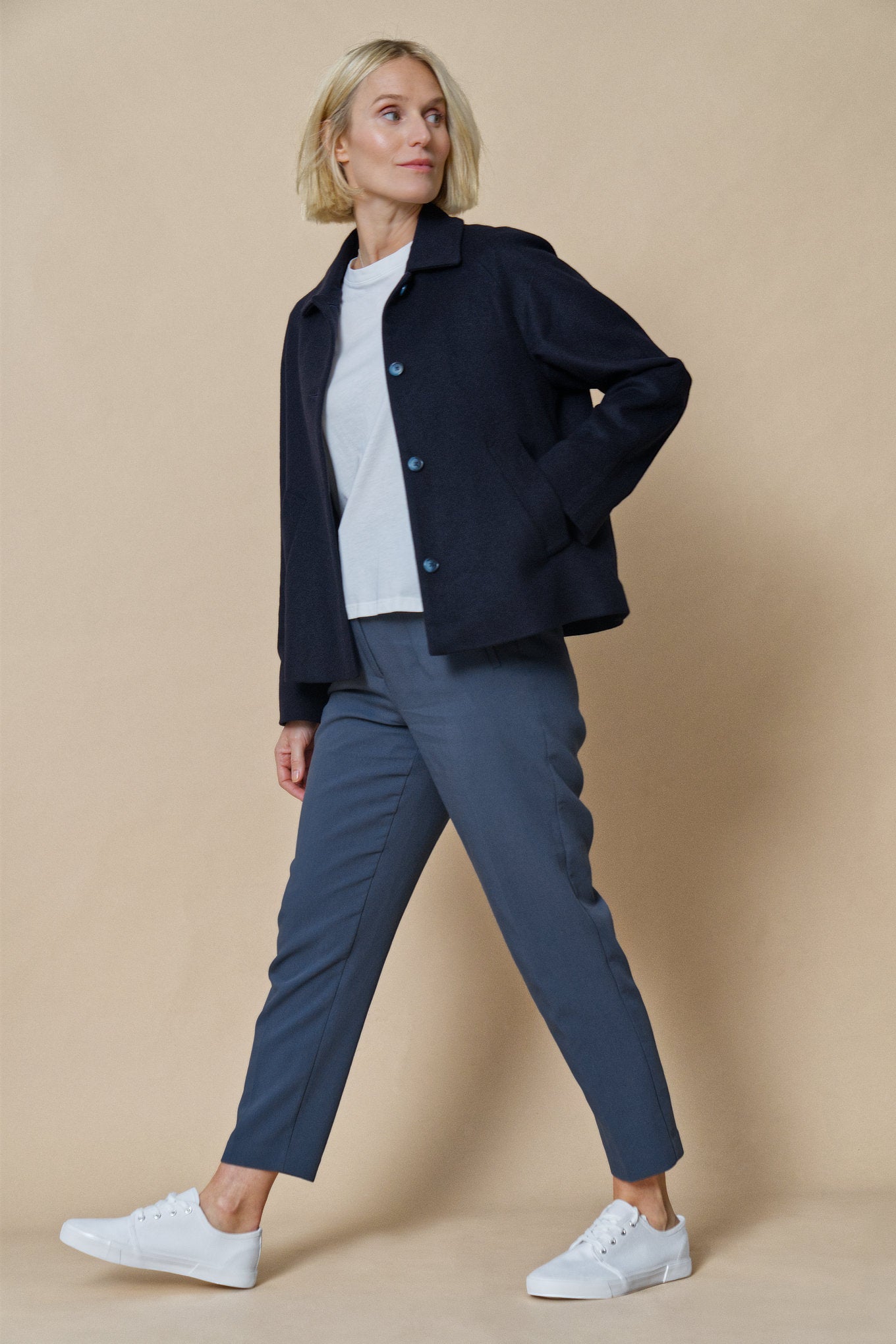 Das Model zeigt unsere Jacke aus Wolle und Kaschmir in der Farbe night blue seitlich mit der rechten Hand in der seitlichen Eingrifftasche.