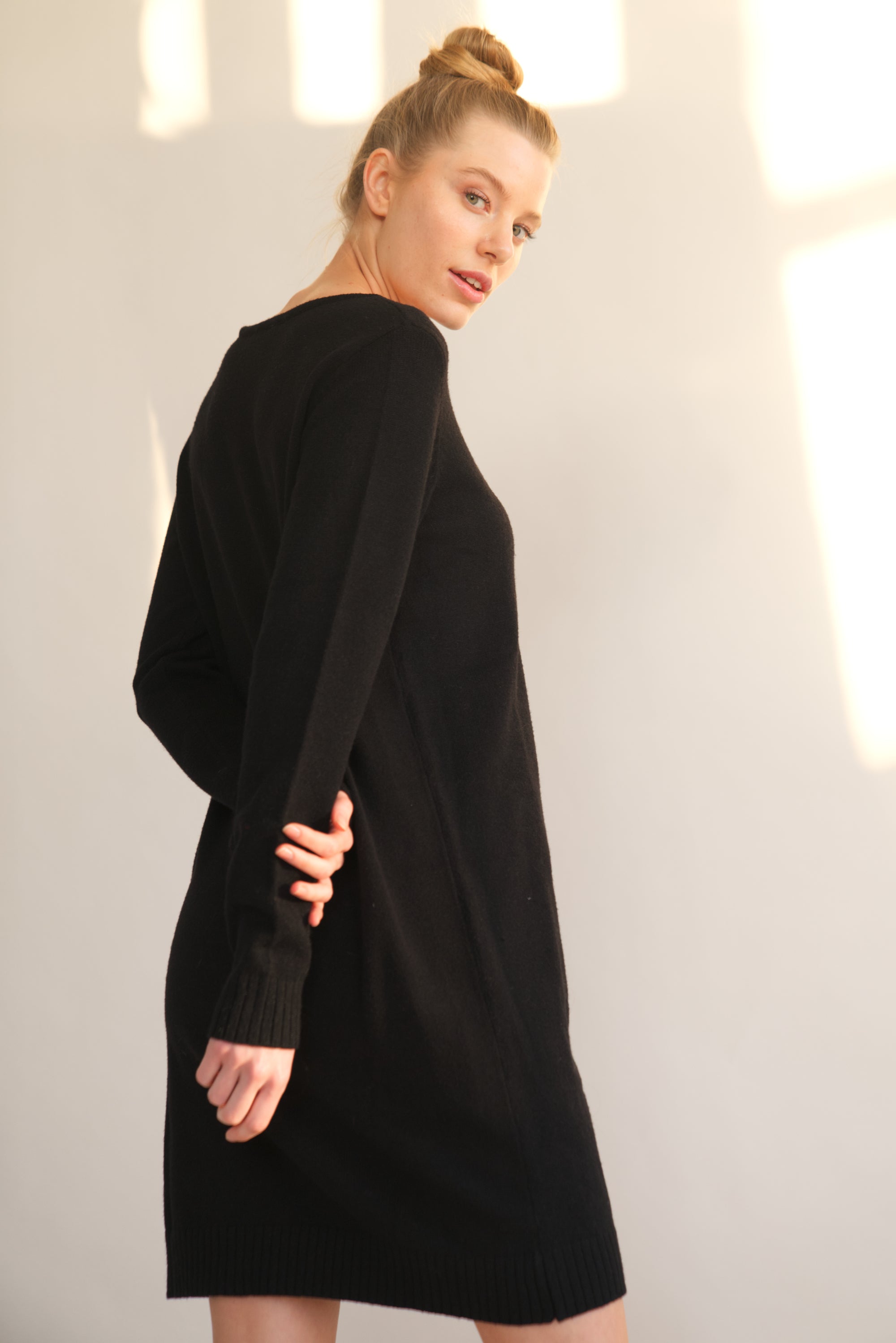Unser Model trägt ein Strickkleid in schwarz von Bellasor. Sie ist seitlich von hinten zu sehen.