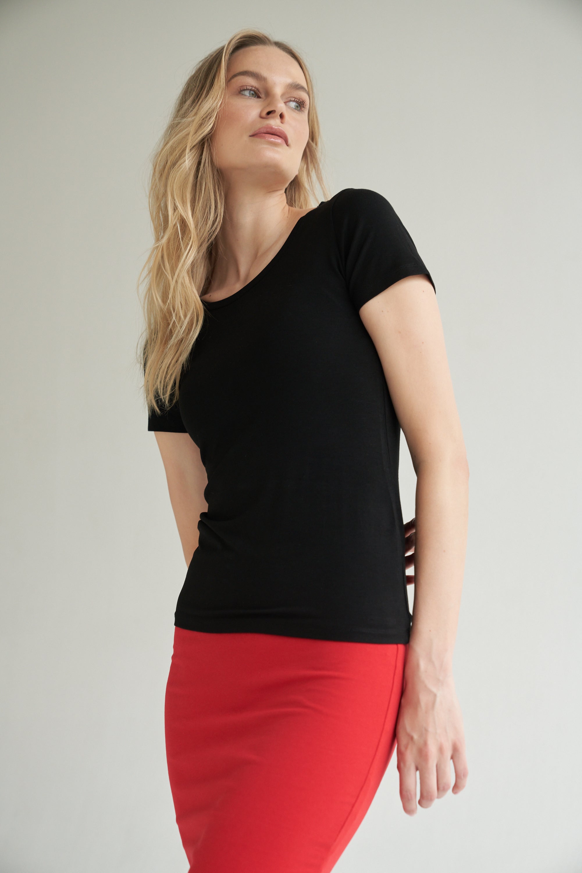 Schwarzes T-Shirt kombiniert mit einem roten Bleistiftrock wird von einem blonden Model getragen.